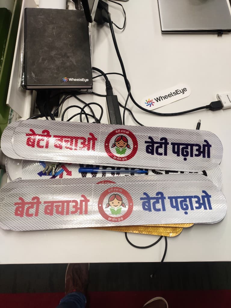 Reflective Beti Bachao Beti Padhao campaign stickers with WheelsEye branding on a desk