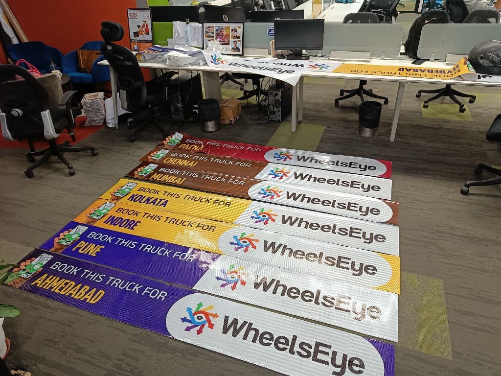 WheelsEye city campaign banners laid out on the office floor for Patna, Chennai, Mumbai, and other cities