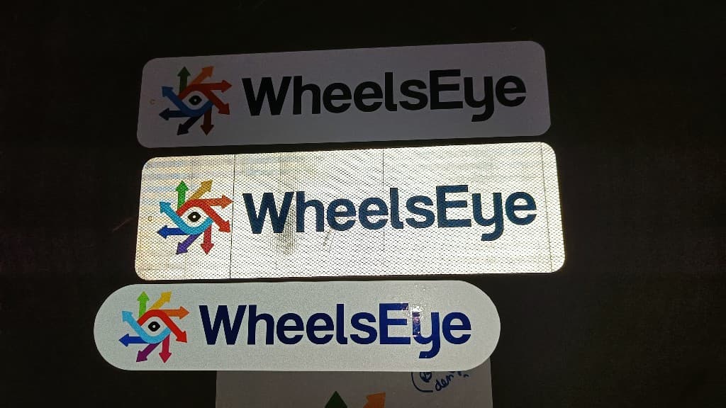 Three WheelsEye sticker design iterations: standard white, reflective hexagonal, and pill-shaped
