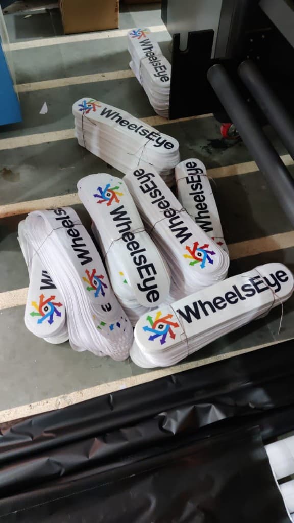 Bundles of freshly printed WheelsEye stickers stacked at a print shop